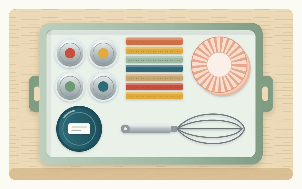 Lift-out bin seen from above holding small jars, a round canister, folded packets, a whisk and a stack of paper cupcake liners