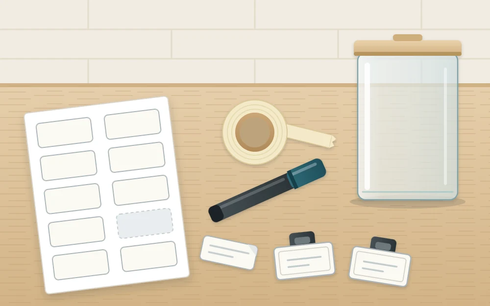 Work surface with a sheet of blank adhesive labels, a marker pen, a roll of tape, two clip-on bin label holders and an empty clear container